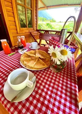 a table with a red and white checkered table cloth with a coffee cup at Yoly cabaña in Oxapampa