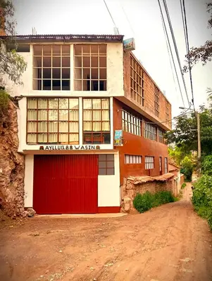 a building with a red door on a dirt road at Guest House Aylluq Wasin in Urubamba