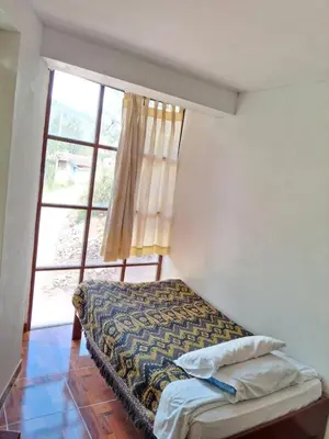 a bed in a room with a large window at Guest House Aylluq Wasin in Urubamba