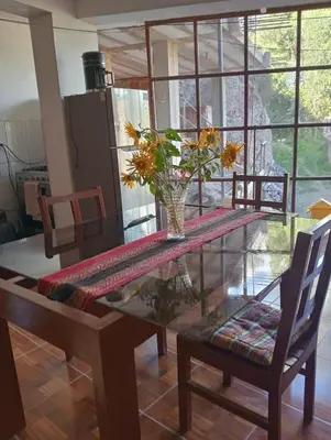a dining room table with a vase of flowers on it at Guest House Aylluq Wasin in Urubamba