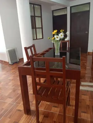 a dining room table with chairs and a vase of flowers at Guest House Aylluq Wasin in Urubamba