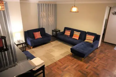 a living room with two blue couches and wooden floors at Casa Canal - 3 cuadras de la Plaza de Armas in Cusco