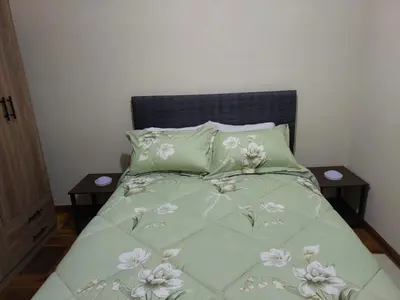 a bed with a green comforter with flowers on it at JTM Apartament in Cusco