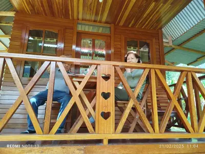 a woman sitting on the porch of a wooden house at Yoly cabaña in San Francisco