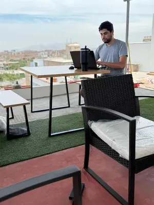 a man sitting at a table with a laptop at Florencia Lodgement in Lima