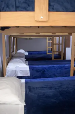 a row of beds under a wooden table at Gutierrez Hostel in Lima