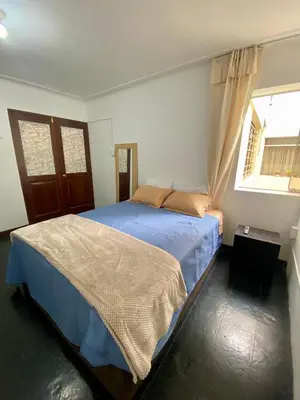a bedroom with a bed with blue sheets and a window at Habitaciones Independientes Av Larco in Lima