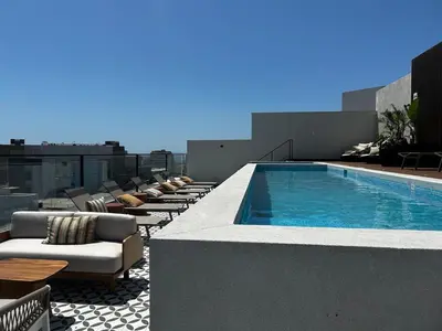 a swimming pool on the roof of a building with lounge chairs at Brand new apartment in Miraflores in Lima