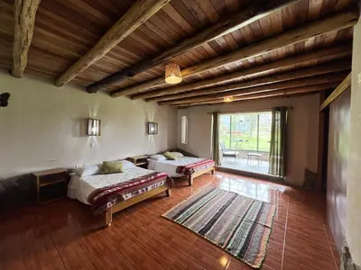 a large room with two beds and a large window at KinsaPacha in Urubamba
