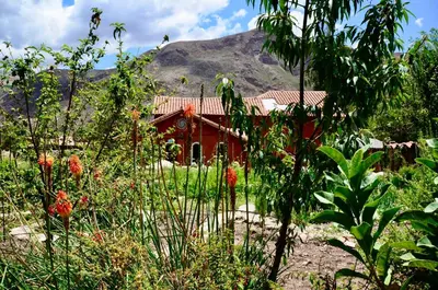 a red house with a mountain in the background at KinsaPacha in Urubamba