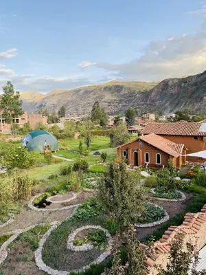 a view of a garden with a house and mountains in the background at KinsaPacha in Urubamba
