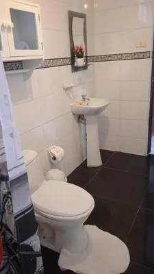 a bathroom with a white toilet and a sink at Studio with kitchen and Bathroom Near The Airport in Lima
