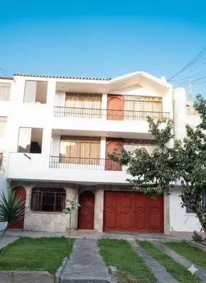 a white building with red doors and a garage at Studio with kitchen and Bathroom Near The Airport in Lima