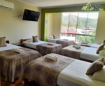 a room with four beds with a tv and a window at Destino Aventura Peru in La Merced