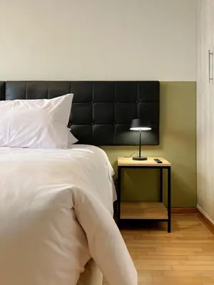 a bed with a black headboard and a table with a lamp at Sky Flatt 2BR by Geko in Lima