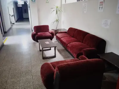 a living room with a red couch and two chairs at Hotel Estación Central in Lima