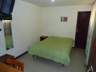 a small bedroom with a green bed and a mirror at Hotel Estación Central in Lima