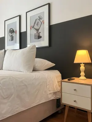 a bedroom with a white bed and a nightstand with a lamp at Barranco Sailor Apartment by Geko in Lima
