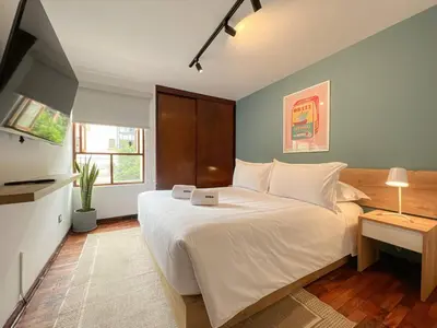 a bedroom with a large white bed and a television at Wood House 3BR by Geko in Lima