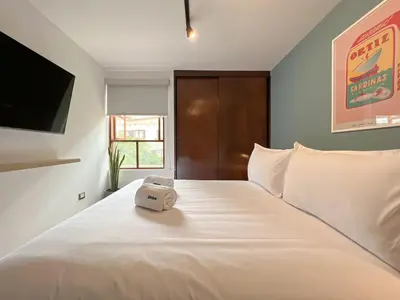 a white bed with a alarm clock on top of it at Wood House 3BR by Geko in Lima