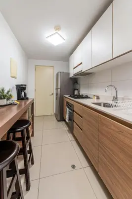a kitchen with wooden cabinets and a stainless steel refrigerator at Midnight District Apartment by Geko in Lima