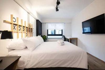 a bedroom with a large white bed with a flat screen tv at Soho by Geko in Lima