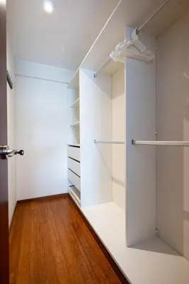 a walk in closet with white walls and wooden floors at Taurus 2BR by Geko in Lima