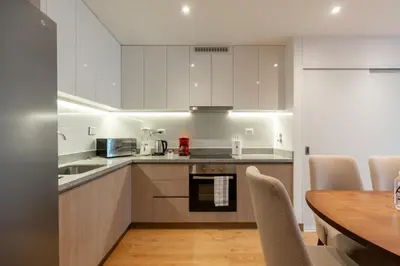 a kitchen with white cabinets and a wooden table at Premium 2BR Apartment Steps from Kennedy Park in Lima