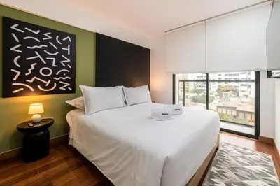 a bedroom with a large white bed and a window at Premium 2BR Apartment Steps from Kennedy Park in Lima