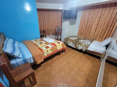 a room with two beds and a chair in a room at Hospedaje Leo in Lima