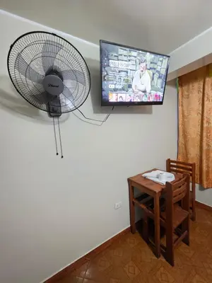 a room with a fan and a table and a tv at Hospedaje Leo in Lima