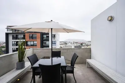 a table and chairs with an umbrella on a balcony at Dopamine Duplex by Geko in Lima
