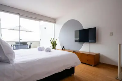 a bedroom with a large bed with a tv on the wall at Dopamine Duplex by Geko in Lima