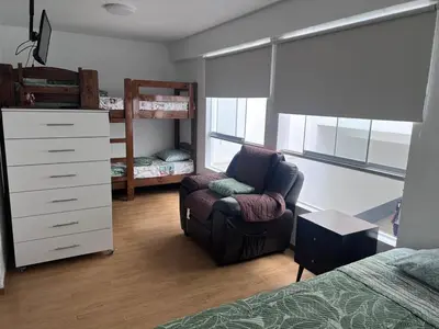 a bedroom with a bed and a chair and a dresser at Alquilo Departamento en Playa Pulpos in Lurín