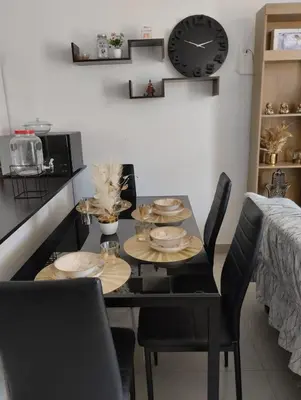 a dining room table with chairs and a clock on the wall at Acogedora casa en ICA - PERU in Ica