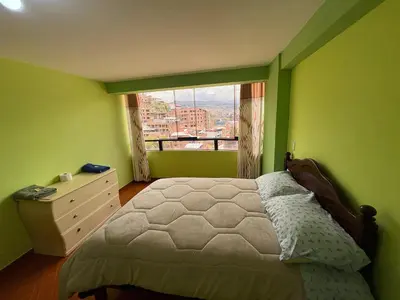 a green bedroom with a bed and a window at Nido Cusqueño in Cusco