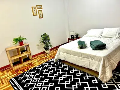a bedroom with a bed with a black and white rug at Casa Raíz Cusco in Cusco