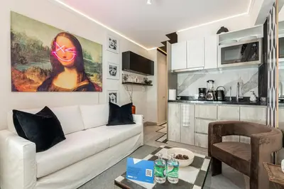 a living room with a white couch and a kitchen at Barranco Modern Apartments with Rooftop Pool by Geko in Lima