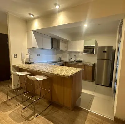 a kitchen with a counter with stools and a refrigerator at Pardo Miraflores Apartment - Aparts 4 Days in Lima