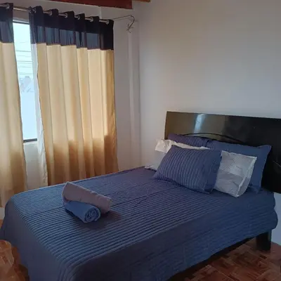 a bed with a blue blanket and a pillow on it at casa de playa en lurin con piscina y parrilla in La Planicie