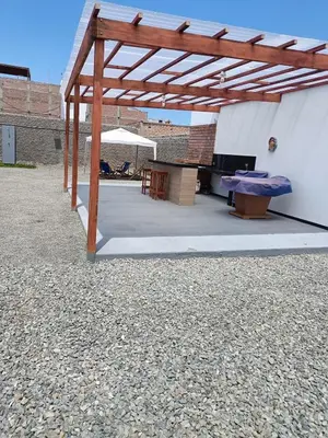 a wooden pavilion with a table and a bench at casa de playa en lurin con piscina y parrilla in La Planicie