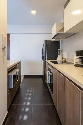 a kitchen with a stainless steel refrigerator and brown cabinets at Grimaldo by Geko in Lima