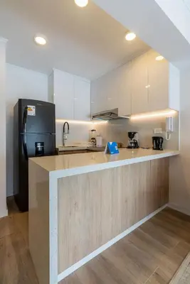 a kitchen with white cabinets and a black refrigerator at Samoa 1BR by Geko in Lima
