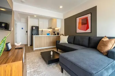 a living room with a blue couch and a kitchen at Samoa 1BR by Geko in Lima