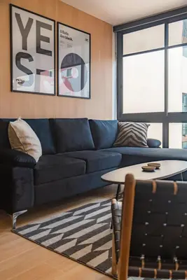 a living room with a blue couch and a table at Vince City 1BR by Geko in Lima