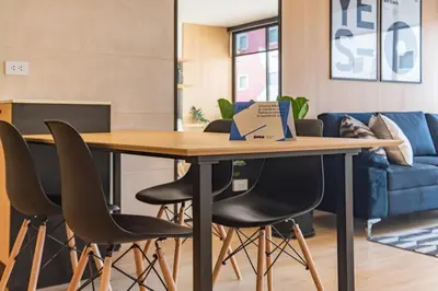 a table in a room with chairs and a couch at Vince City 1BR by Geko in Lima