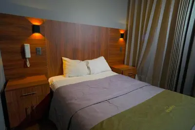 a small bedroom with a bed and wooden walls at Hotel Qhawaq Huancayo in Huancayo