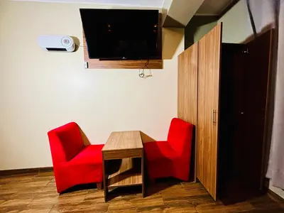 a room with two red chairs and a table and a tv at Hotel Qhawaq Huancayo in Huancayo
