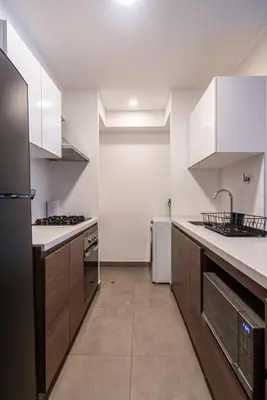a kitchen with white cabinets and a black refrigerator at The Oak 2BR by Geko in Lima