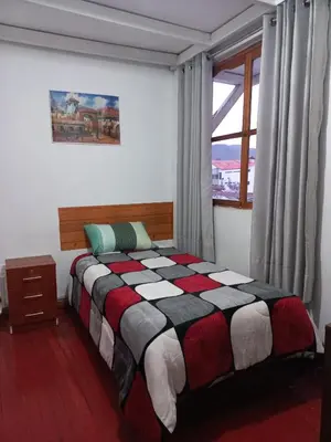 a bedroom with a bed and a window at Posada Escondida in Cusco